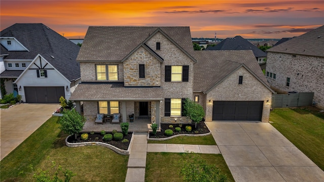 traditional-style home with covered porch, a shingled roof, a front lawn, and concrete driveway