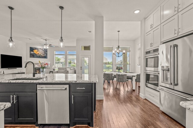 kitchen featuring appliances with stainless steel finishes, light stone countertops, a sink, and plenty of natural light
