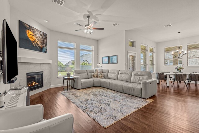 living area with dark wood-style flooring, ceiling fan with notable chandelier, visible vents, and a fireplace