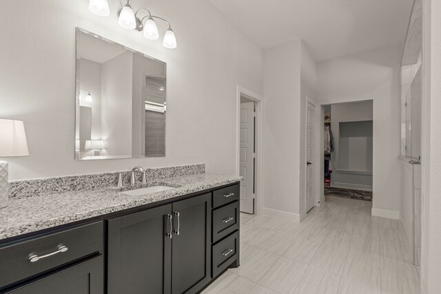 bathroom featuring baseboards, a spacious closet, and vanity