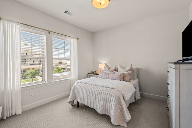 bedroom featuring baseboards, visible vents, and light carpet