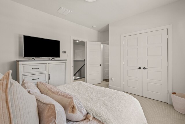 bedroom featuring light colored carpet, visible vents, and a closet