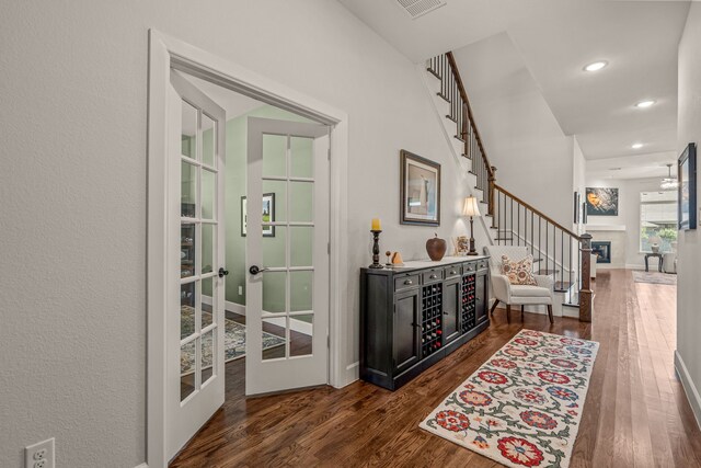 interior space featuring stairway, a glass covered fireplace, french doors, dark wood-style flooring, and recessed lighting
