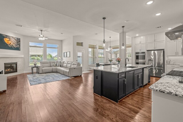 kitchen with white cabinets, a tiled fireplace, dark wood finished floors, appliances with stainless steel finishes, and recessed lighting
