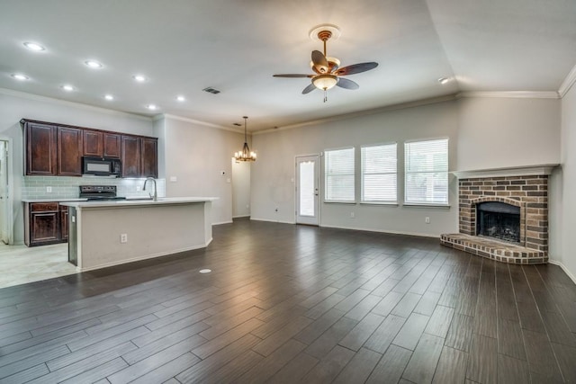 kitchen featuring light countertops, a sink, black appliances, open floor plan, and ceiling fan with notable chandelier