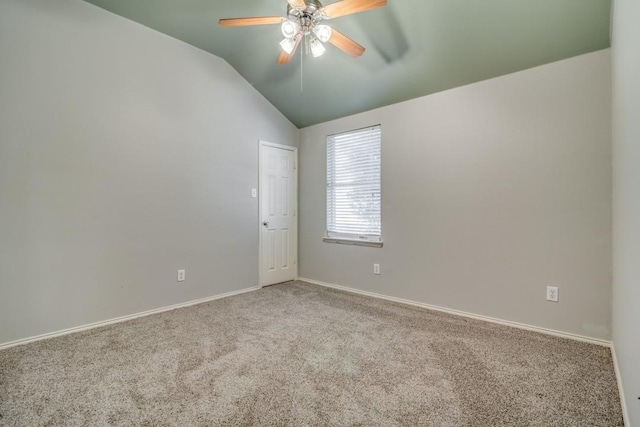 empty room featuring lofted ceiling, carpet floors, a ceiling fan, and baseboards