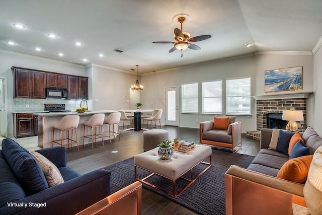 living room featuring ceiling fan with notable chandelier, dark wood-type flooring, and recessed lighting