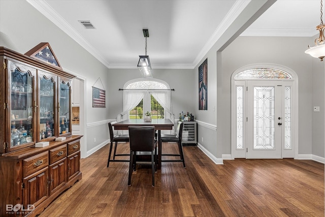 dining room featuring dark wood-type flooring, visible vents, baseboards, and ornamental molding
