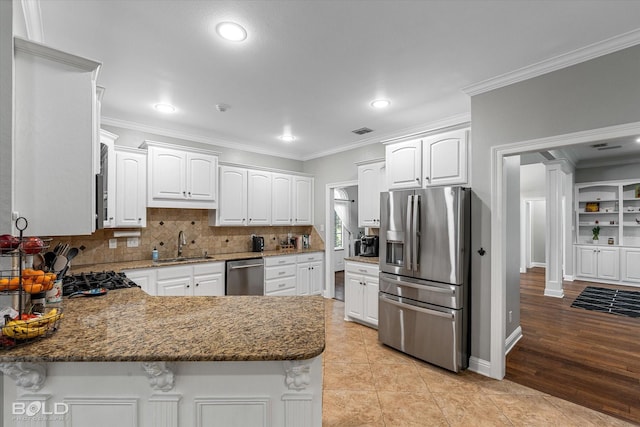 kitchen featuring stainless steel appliances, a peninsula, a sink, visible vents, and ornamental molding