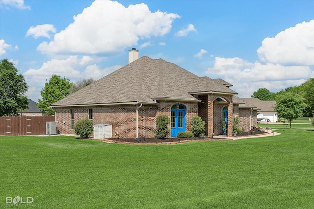 view of front of house with brick siding, a shingled roof, a front lawn, and central AC unit