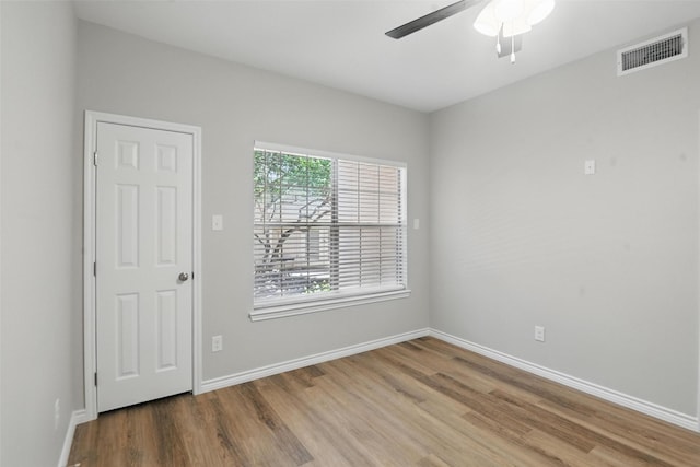 spare room with baseboards, wood finished floors, visible vents, and ceiling fan
