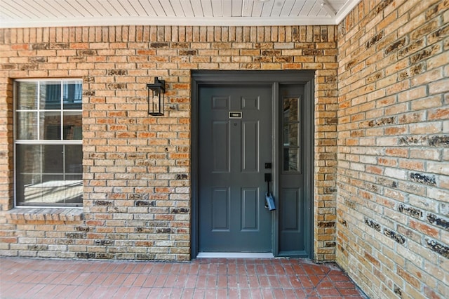 view of exterior entry featuring brick siding