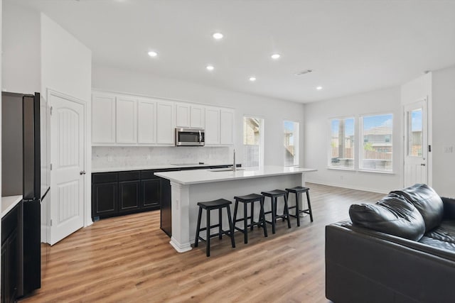 3120 Bent Creek Dr, Anna, TX 75409 - kitchen with black appliances, open floor plan, a kitchen breakfast bar, light wood-style flooring, and decorative backsplash
