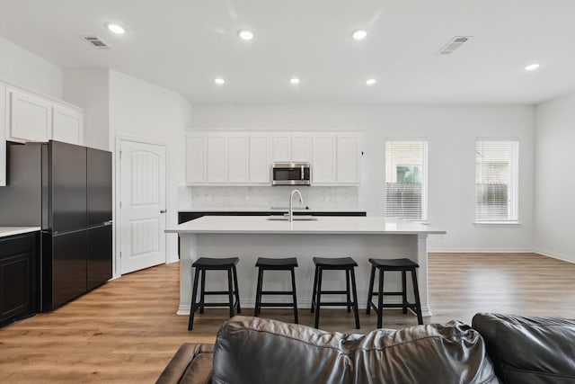 3120 Bent Creek Dr, Anna, TX 75409 - kitchen with stainless steel microwave, a sink, freestanding refrigerator, open floor plan, and light countertops