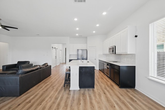 3120 Bent Creek Dr, Anna, TX 75409 - kitchen featuring appliances with stainless steel finishes, open floor plan, a sink, light wood-type flooring, and a kitchen breakfast bar