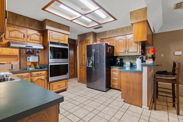 1502 Hinchliffe Rd, Mexia, TX 76667 - kitchen featuring stainless steel appliances, a peninsula, washer and clothes dryer, visible vents, and a breakfast bar