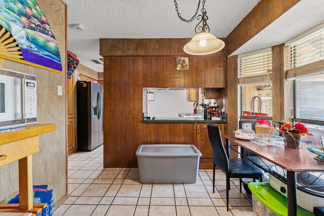 1502 Hinchliffe Rd, Mexia, TX 76667 - kitchen featuring brown cabinetry, light tile patterned flooring, white microwave, and stainless steel fridge