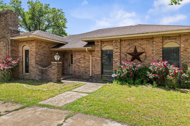 1502 Hinchliffe Rd, Mexia, TX 76667 - view of front of home with a chimney, brick siding, roof with shingles, and a front yard