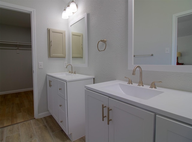 405 Derby Ln, Desoto, TX 75115 - bathroom featuring two vanities, wood finished floors, a sink, and a walk in closet