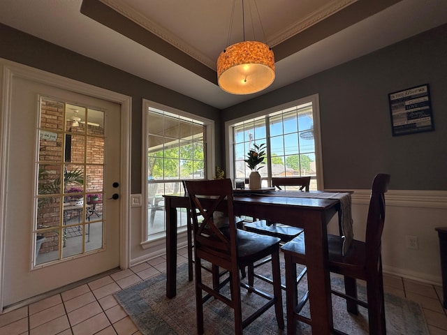 dining area featuring a raised ceiling, baseboards, ornamental molding, and light tile patterned floors
