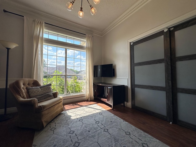 living area featuring dark wood-style floors, a textured ceiling, baseboards, a notable chandelier, and crown molding