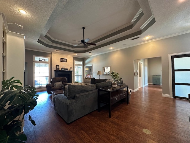 living room with ceiling fan, dark wood-style flooring, a tray ceiling, and a textured ceiling