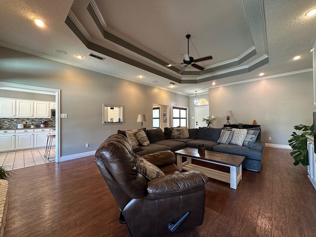 living room with dark wood finished floors, a raised ceiling, crown molding, and ceiling fan