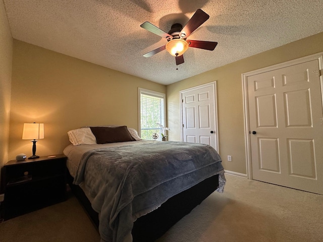 carpeted bedroom with a textured ceiling, baseboards, and ceiling fan