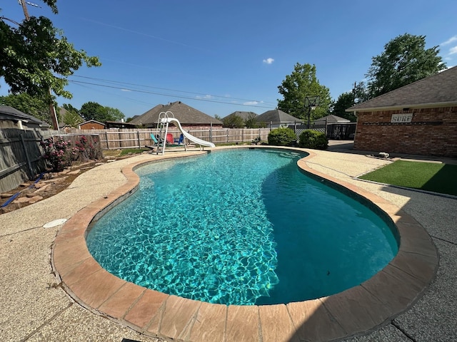 view of pool featuring a fenced backyard, a water slide, a fenced in pool, and a patio
