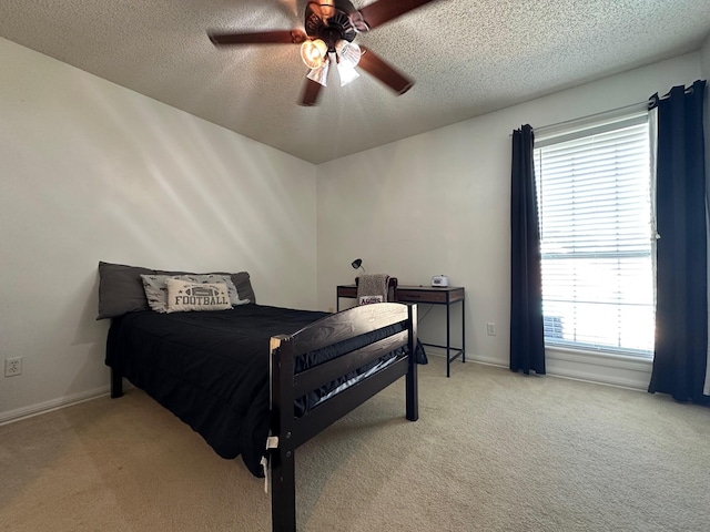 bedroom with light carpet, a ceiling fan, and a textured ceiling