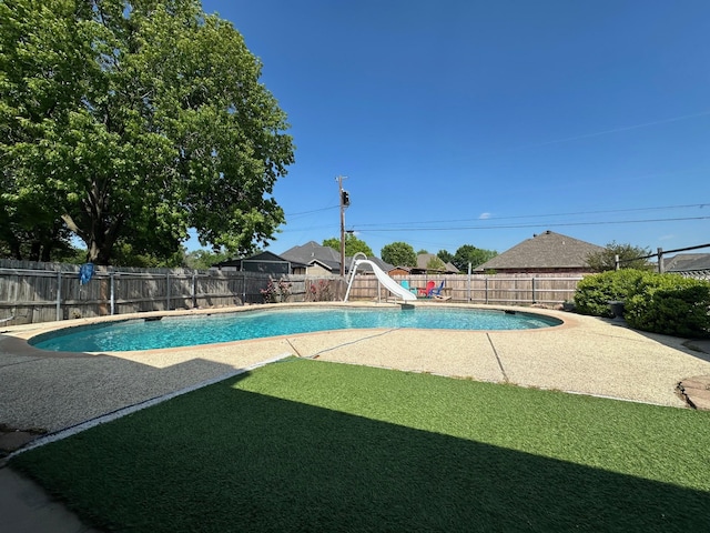 view of swimming pool with a water slide, a fenced in pool, a fenced backyard, a yard, and a patio area