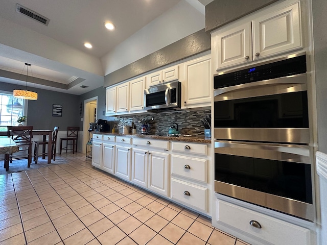 kitchen featuring decorative backsplash, light tile patterned flooring, stainless steel appliances, white cabinetry, and visible vents