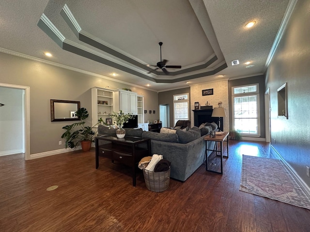 living room with ceiling fan, dark wood-style flooring, crown molding, and a tray ceiling
