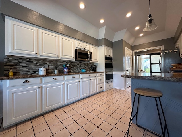 kitchen with tasteful backsplash, stainless steel appliances, white cabinetry, and light tile patterned floors