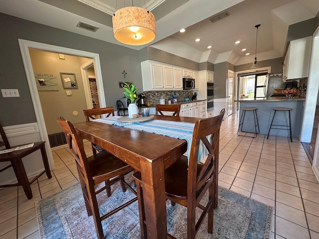 dining room featuring visible vents, light tile patterned floors, and a tray ceiling