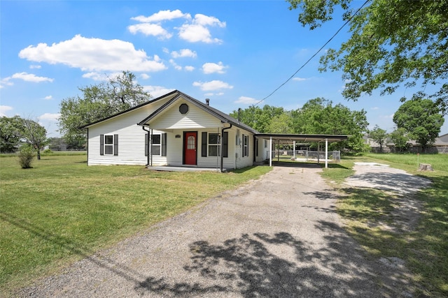 bungalow-style house featuring covered porch, driveway, a front yard, and a carport