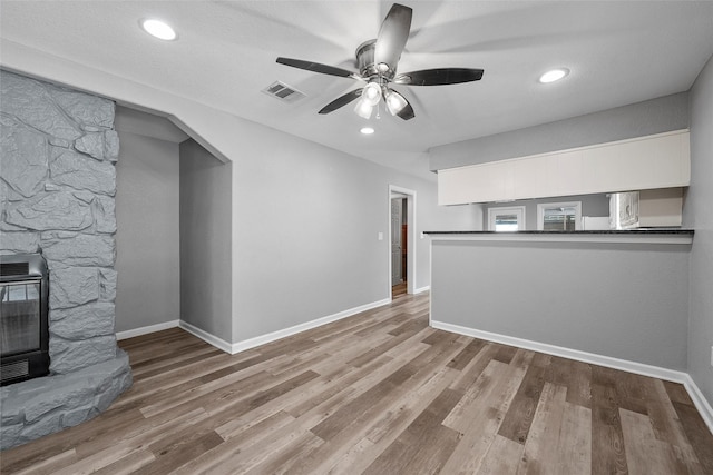 117 W Craven Ave, Lacy Lakeview, TX 76705 - unfurnished living room featuring heating unit, a wood stove, ceiling fan, wood finished floors, and recessed lighting