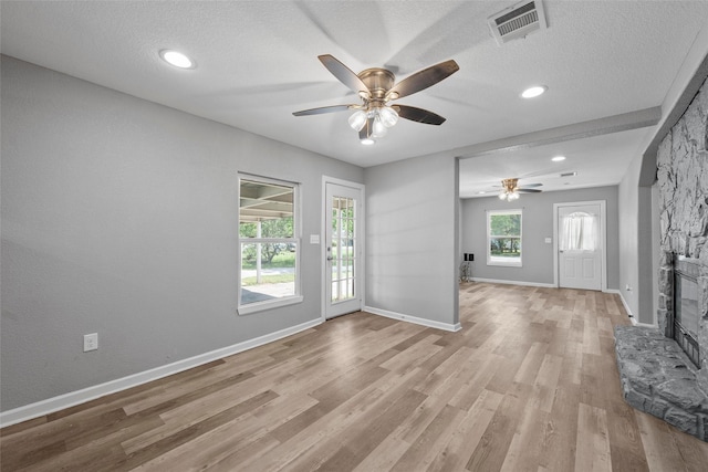117 W Craven Ave, Lacy Lakeview, TX 76705 - unfurnished living room featuring ceiling fan, a stone fireplace, light wood-style floors, a textured ceiling, and recessed lighting