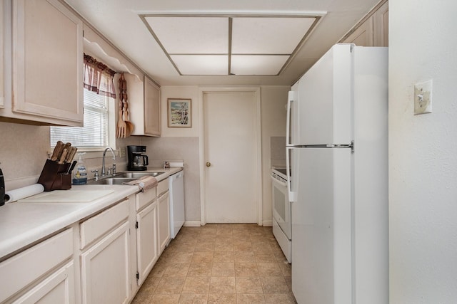kitchen featuring light countertops, white appliances, and a sink