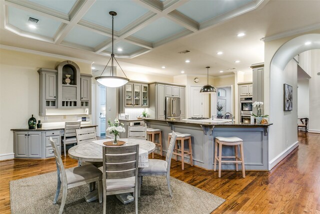 dining room featuring crown molding, beamed ceiling, wood finished floors, and coffered ceiling