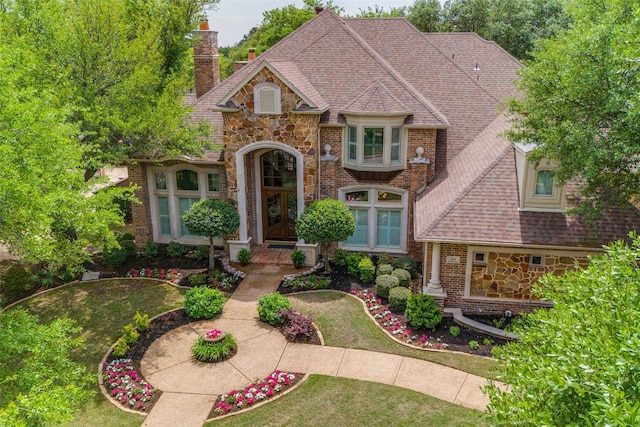 view of front of property with roof with shingles, a chimney, french doors, and stone siding