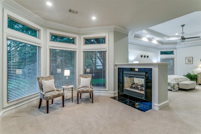 sitting room featuring carpet flooring, baseboards, a tile fireplace, visible vents, and ornamental molding