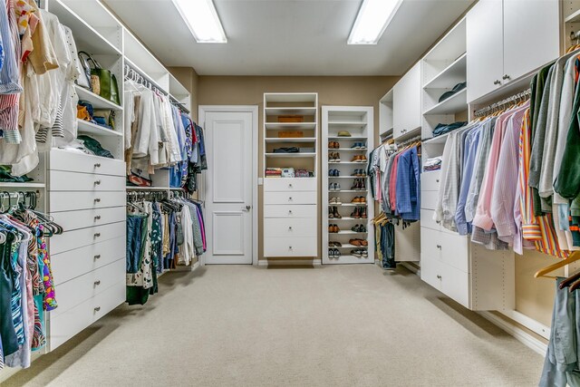 walk in closet featuring light colored carpet