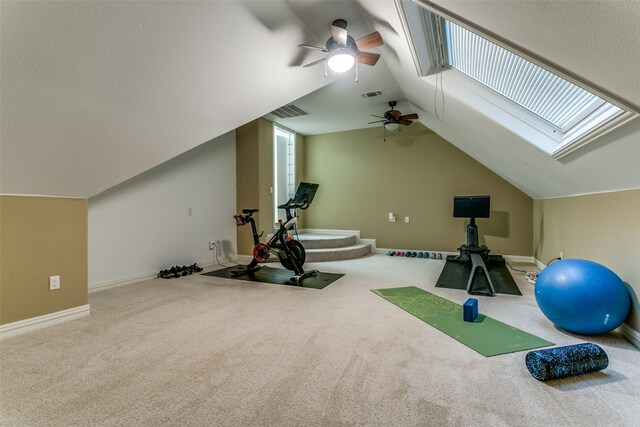 exercise area featuring carpet floors, a ceiling fan, visible vents, and lofted ceiling with skylight