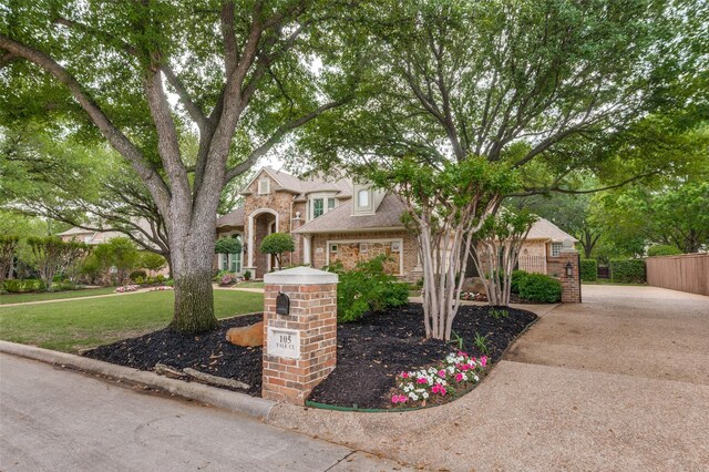 traditional home featuring brick siding, fence, and a front lawn