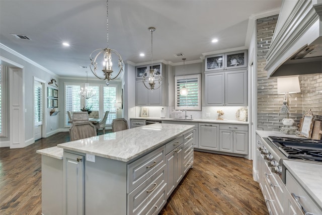 kitchen featuring a center island, a sink, an inviting chandelier, custom range hood, and visible vents