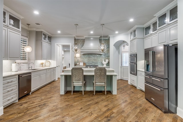 kitchen featuring premium range hood, backsplash, appliances with stainless steel finishes, and light countertops