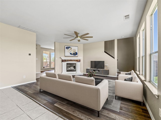 living room featuring baseboards, a ceiling fan, a glass covered fireplace, and visible vents
