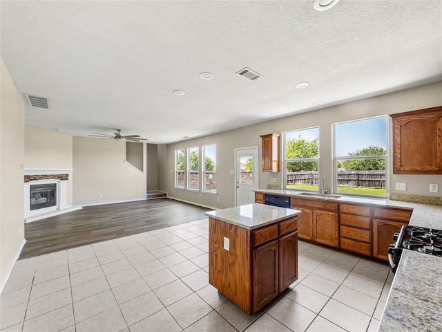 kitchen with visible vents, a center island, light tile patterned floors, and a sink