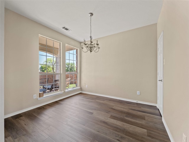 unfurnished room with baseboards, visible vents, a notable chandelier, and dark wood-style flooring
